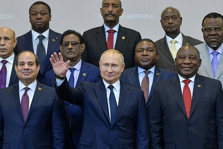 A group of men in suits, one raising his hand in greeting