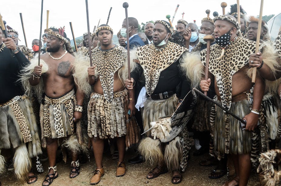 A group of men carrying sticks and wearing leopard skins