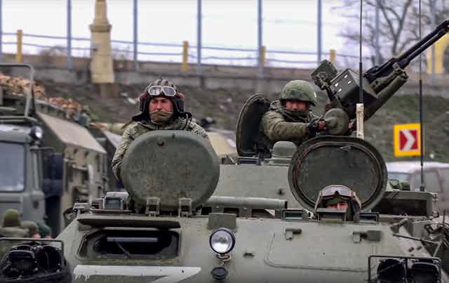Two Russian servicemen driving armoured military vehicles