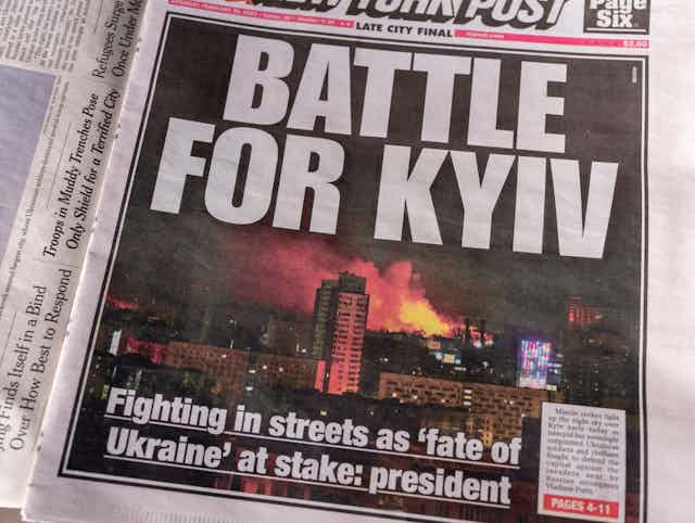 "BATTLE FOR KYIV" blares a page one newspaper headline, with a photo of burning buildings in Kyiv.