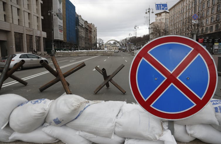 A roadblock in Kyiv with hedgehogs, sandbags and a stop sign.
