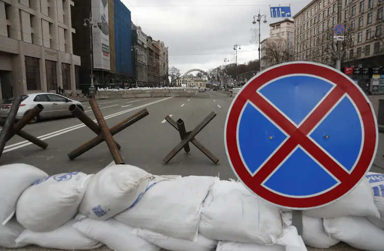 A roadblock in Kyiv with hedgehogs, sandbags and a stop sign.