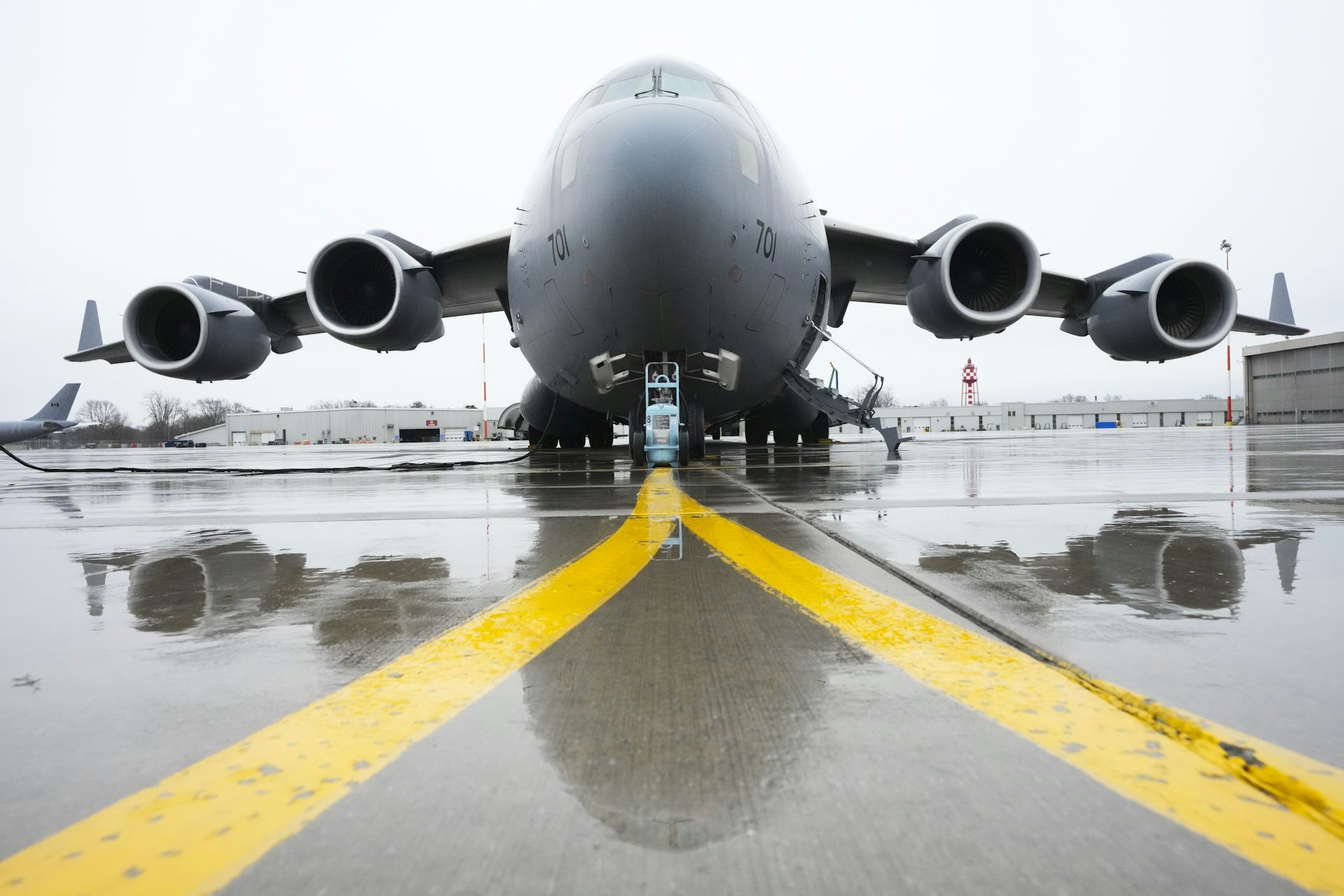 A large jetliner sits on a tarmac with yellow lines in the foreground.