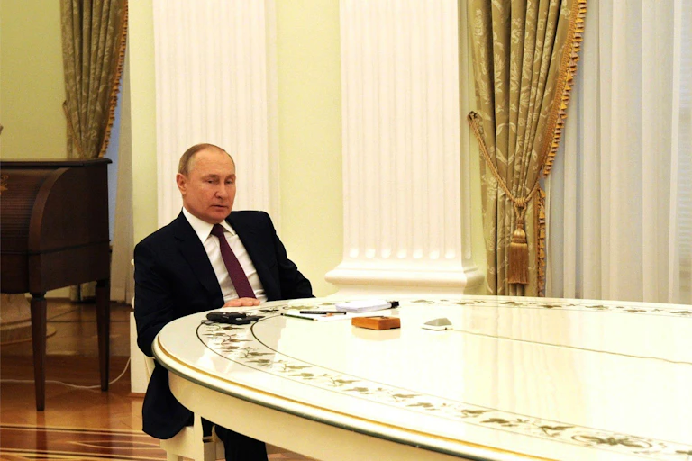 Vladimir Putin sits alone at his negotiating table in the Kremlin.