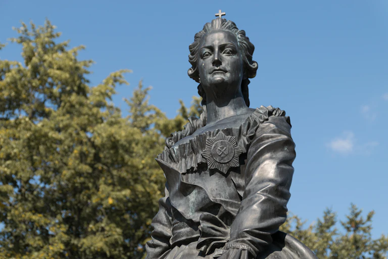A stone monument of a woman with trees in the background.