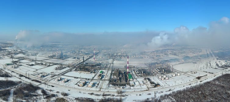 Broad view of oil tanks, refinery buildings and tall smokestacks