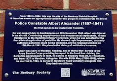 blue plaque with white text on brick wall