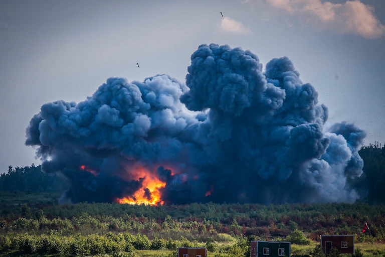 Photographie montrant une large nuage de fumée noire, avec un grand brasier au centre