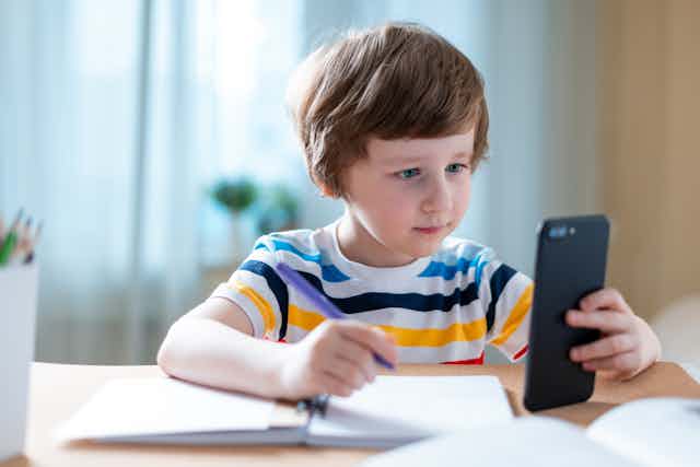 Boy doing schoolwork looking at phone