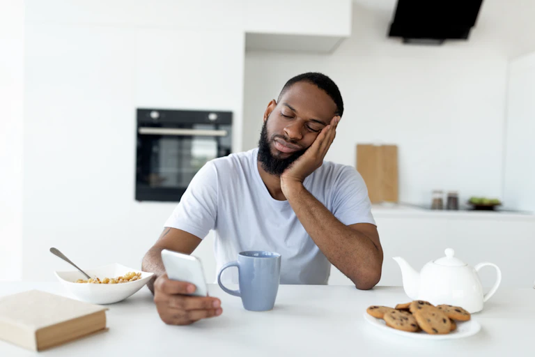 Image of a man looking apathetic while scrolling on his phone.