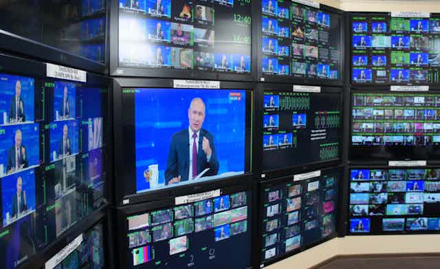 Many television screens showing President Putin speaking