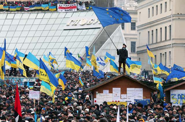 Thousands of protestors gathering in Kyiv in 2013, waving Ukrainian and European flags.