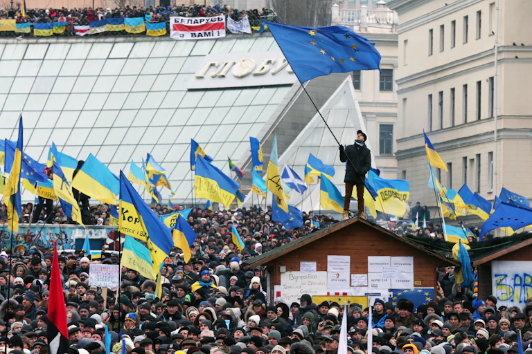 Thousands of protestors gathering in Kyiv in 2013, waving Ukrainian and European flags.