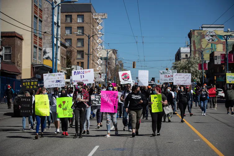 People holding signs in support of safer drug supply marching in a street