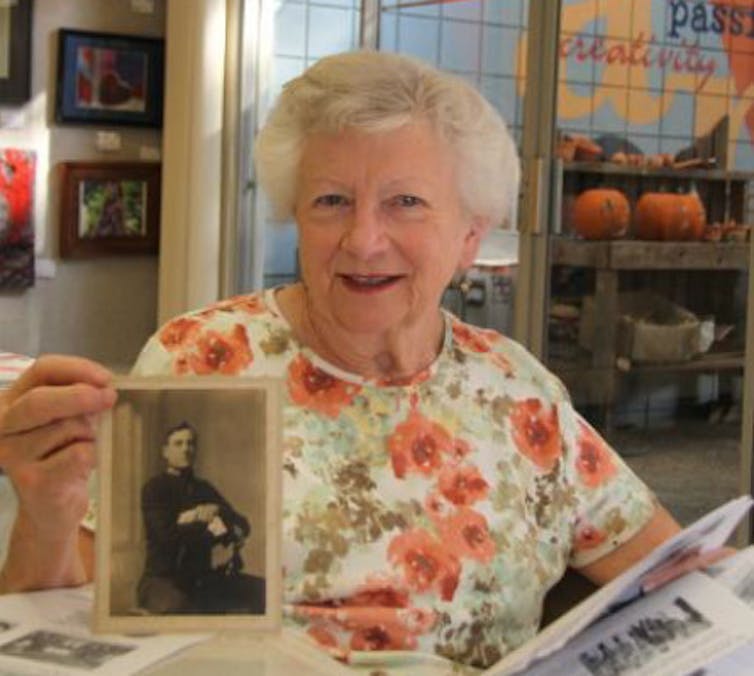 elderly woman holds up a black and white photo