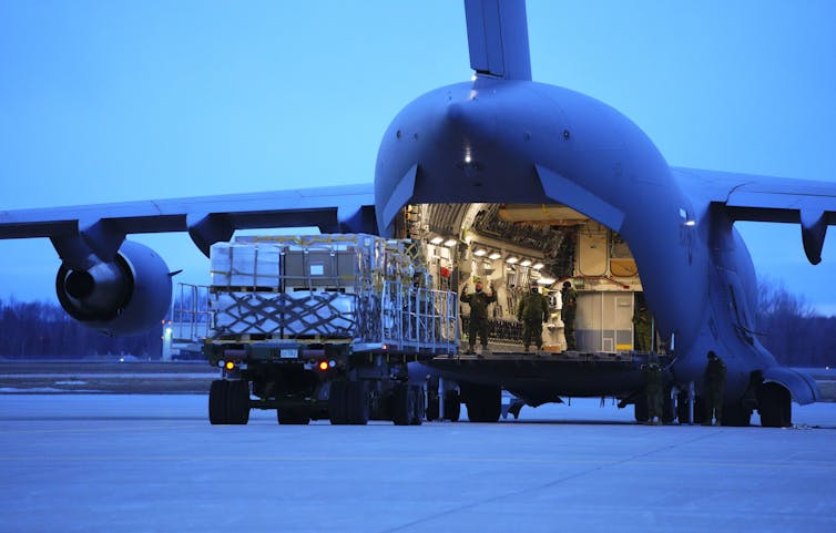 Soldiers load cargo into a military cargo jet.