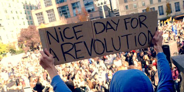 Protester holding sign that reads: 'Nice day for a revolution.'