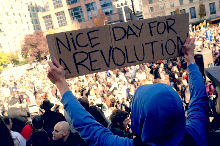 Protester holding sign that reads: 'Nice day for a revolution.'
