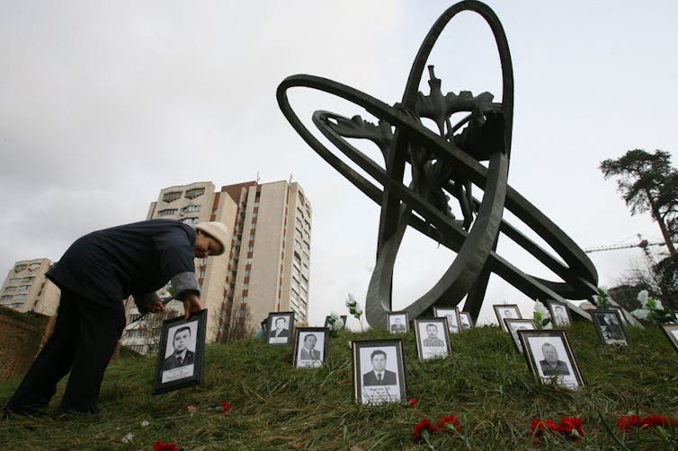 Une vieille dame dépose la photo d’un liquidateur au pied du mémorial dédié de Kiev