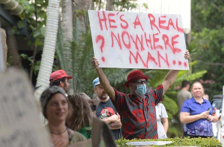 person holds sign saying 'he's a real nowhere man'