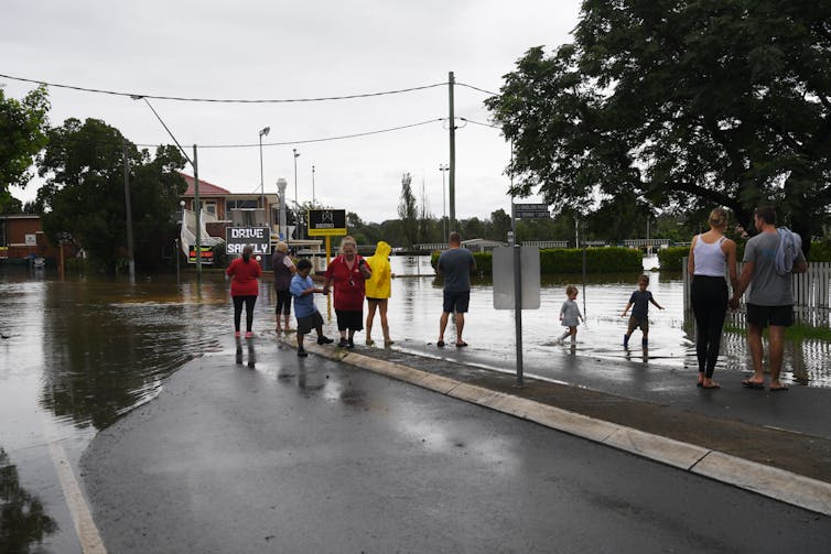 Community members look at rising water levels on their street