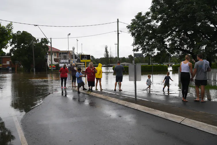 Community members look at rising water levels on their street