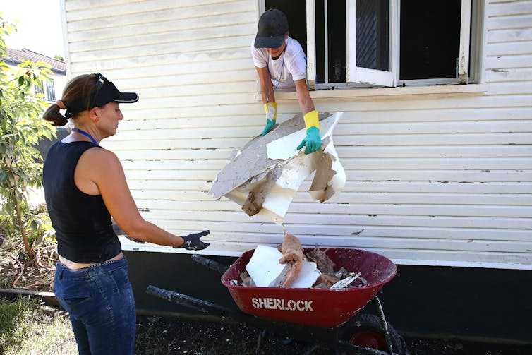 People clean a flood-affected house