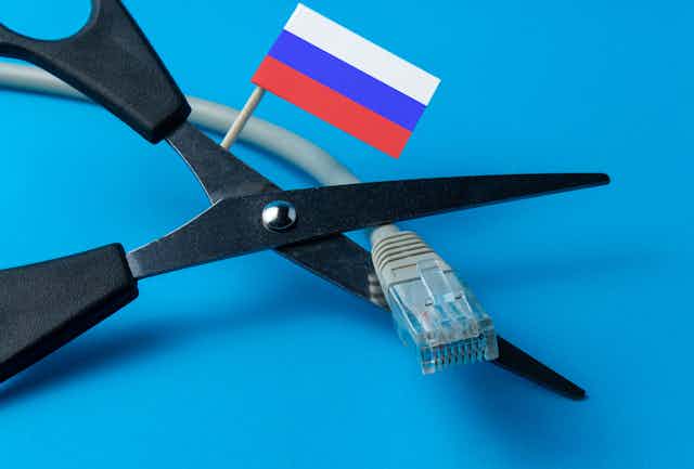 Scissors are cutting an internet wire, with a small Russian flag poking out from behind.