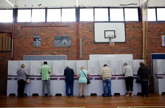People with backs turned at the polling booth.