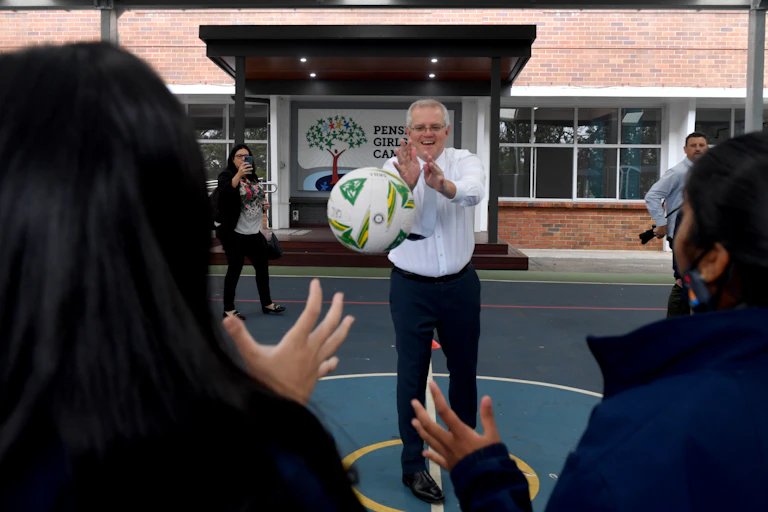Man throws a netball towards two schoolgirls