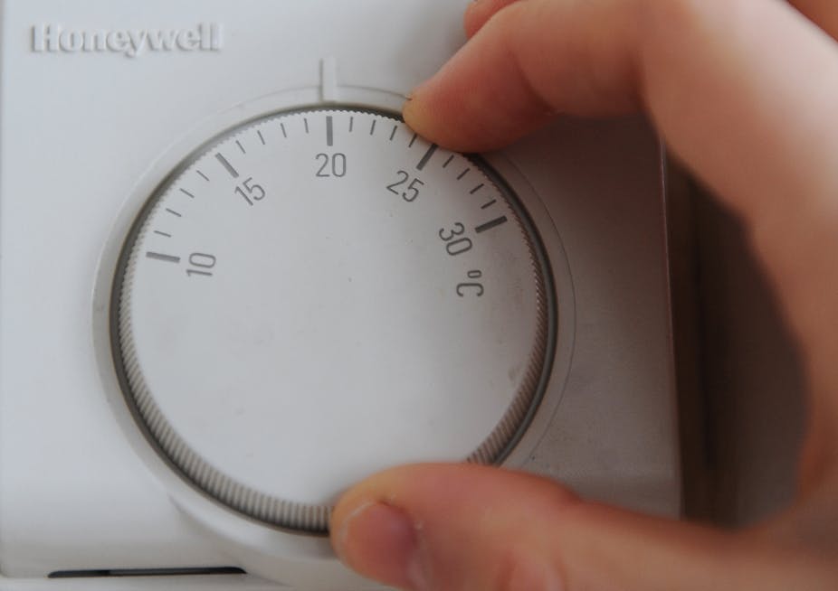 A hand turning the wheel on a thermostat.