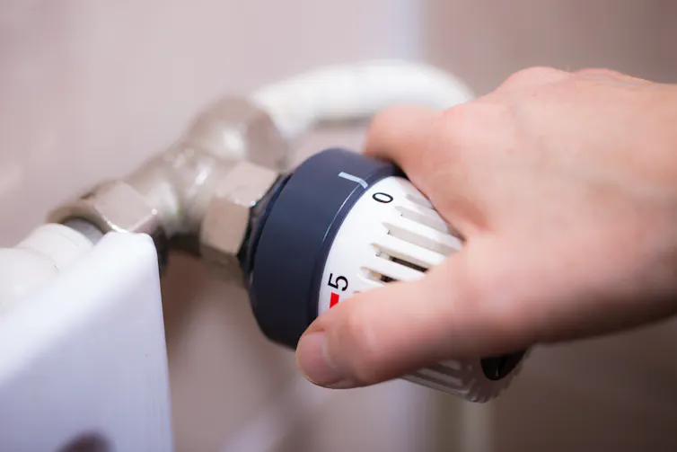 A hand turning the knob on a radiator.
