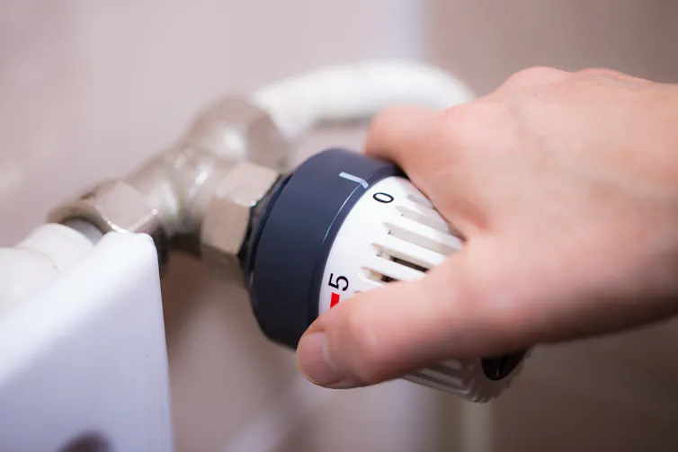 A hand turning the knob on a radiator.