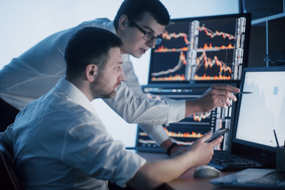 Two financial traders studying screens