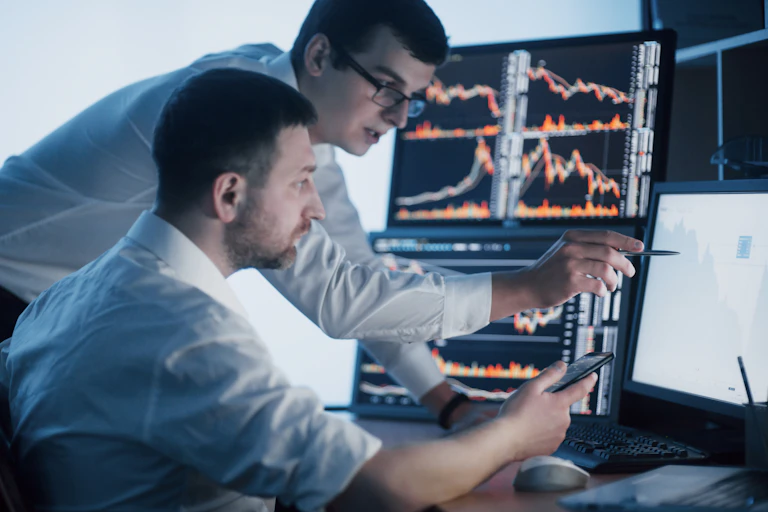 Two financial traders studying screens