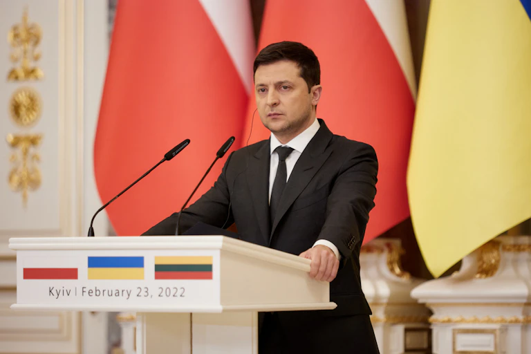President Zelensky of Ukraine standing at a podium looking very grave.