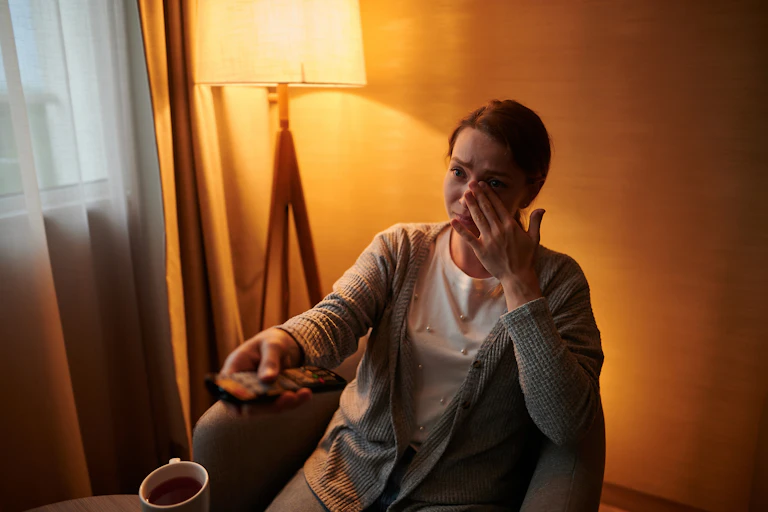 Woman watching TV, crying.