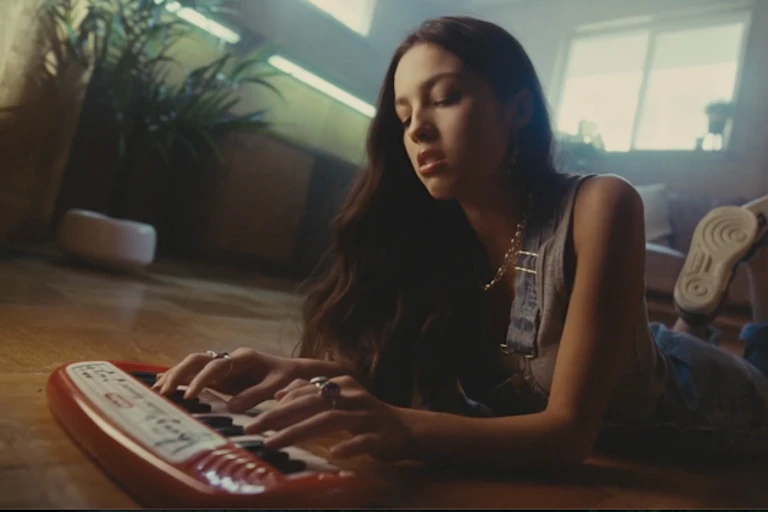 Young girl playing with a child's keyboard, lying on the floor