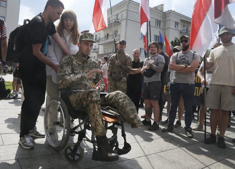 A man in battle fatigues in a wheelchair with a missing left foot.