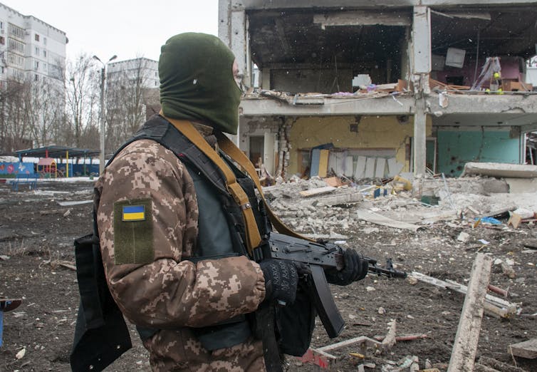Ukrainian in a residential area of Kharkiv in front of a half-destroyed apartment block.