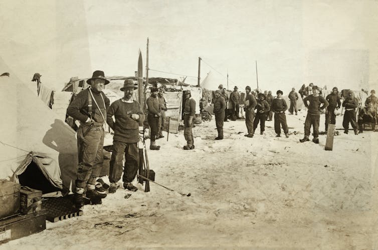 A black-and-white photo of men in winter clothing standing on ice