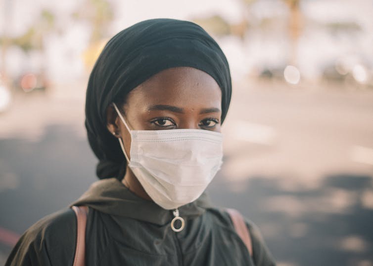 A young person in a face mask wearing a hijab.