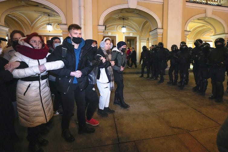 Protesters link arms as they face Russian police trying to shut down the protest