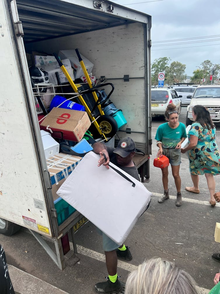 People are loading items into the back of a truck.