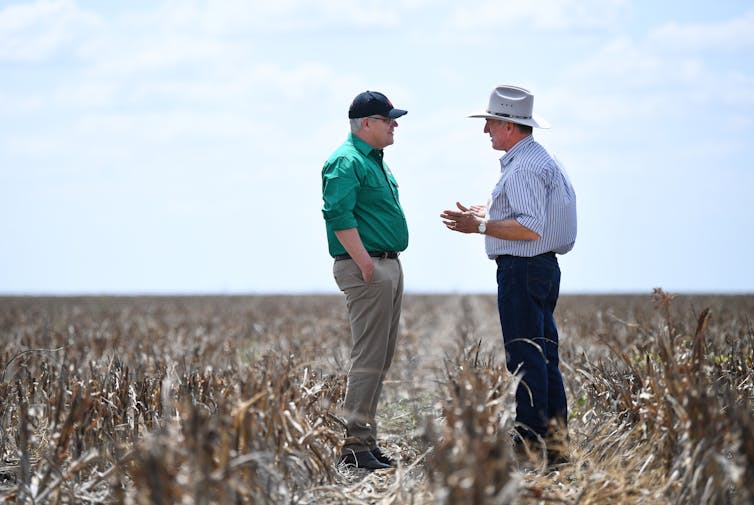 two men talk in dry field