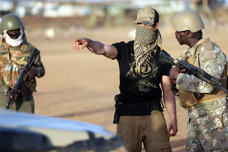 Three men in military uniform and carrying guns