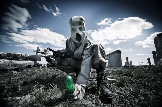 Soldiers in biohazard suits in a conflict zone.
