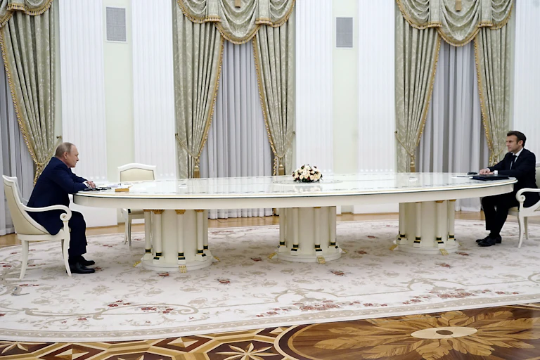 Vladimir Putin and Emmanuel Macron sitting at either end of a very long table in Moscow