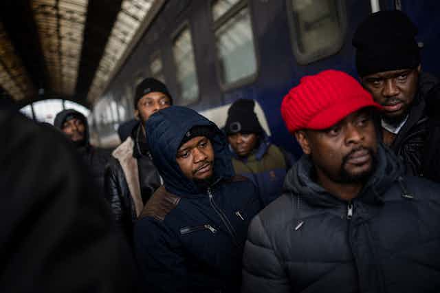 a group of black men wait on a train station