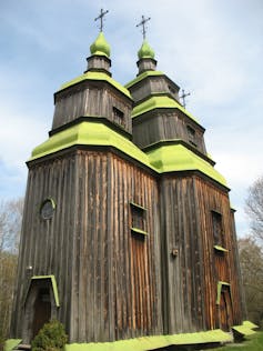 A wooden church with green roof detail.